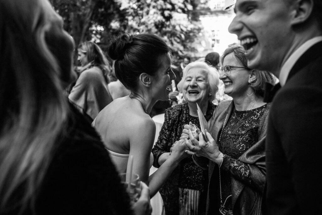 Reporterska fotografia ślubna - WhiteSmoke Studio 34 Śmiech gości podczas przyjęcia w ogrodzie