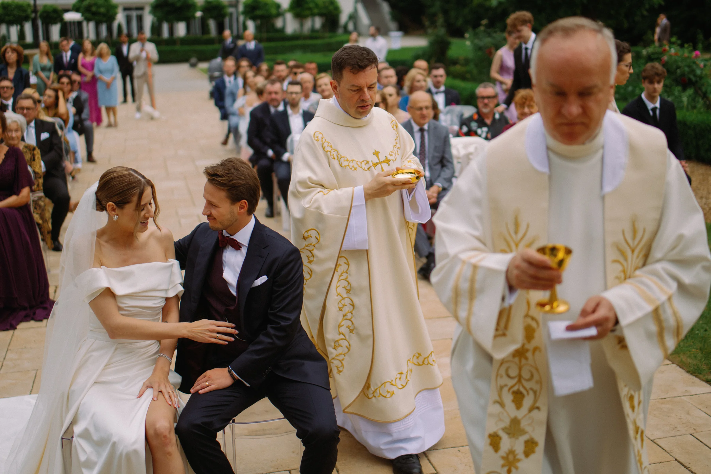 Martyna i Maks siedzą podczas ceremonii, goście w tle