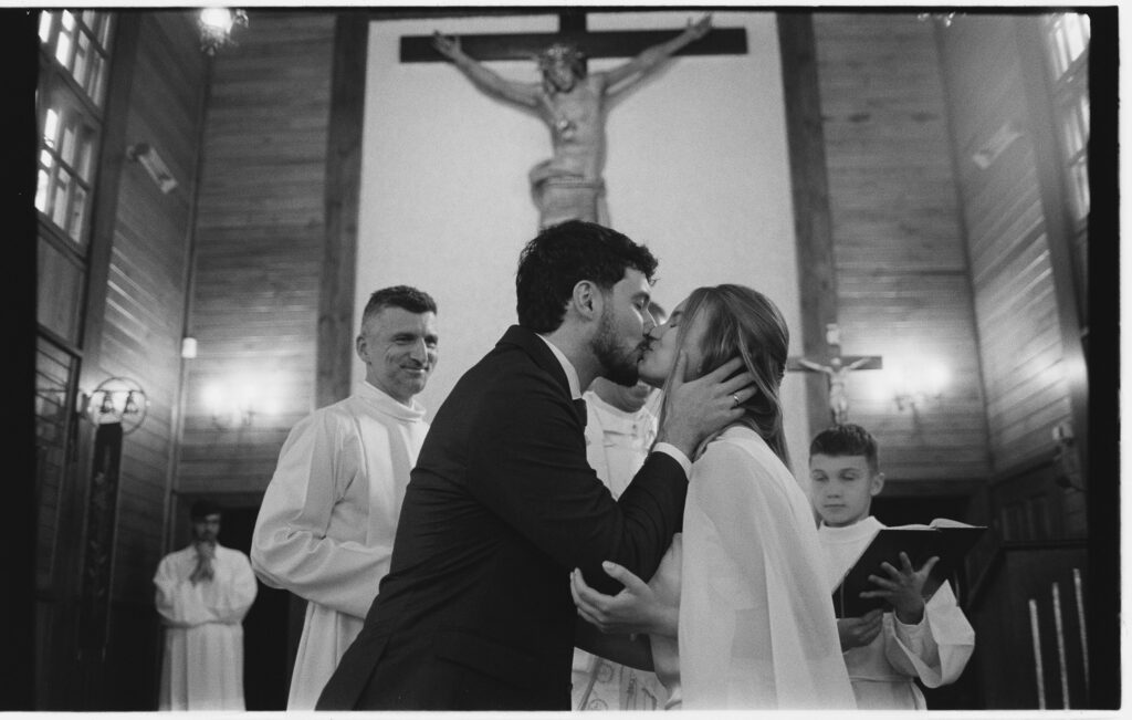 Reporterska fotografia ślubna - WhiteSmoke Studio 44 Pocałunek pary młodej podczas ceremonii na filmie czarno-białym