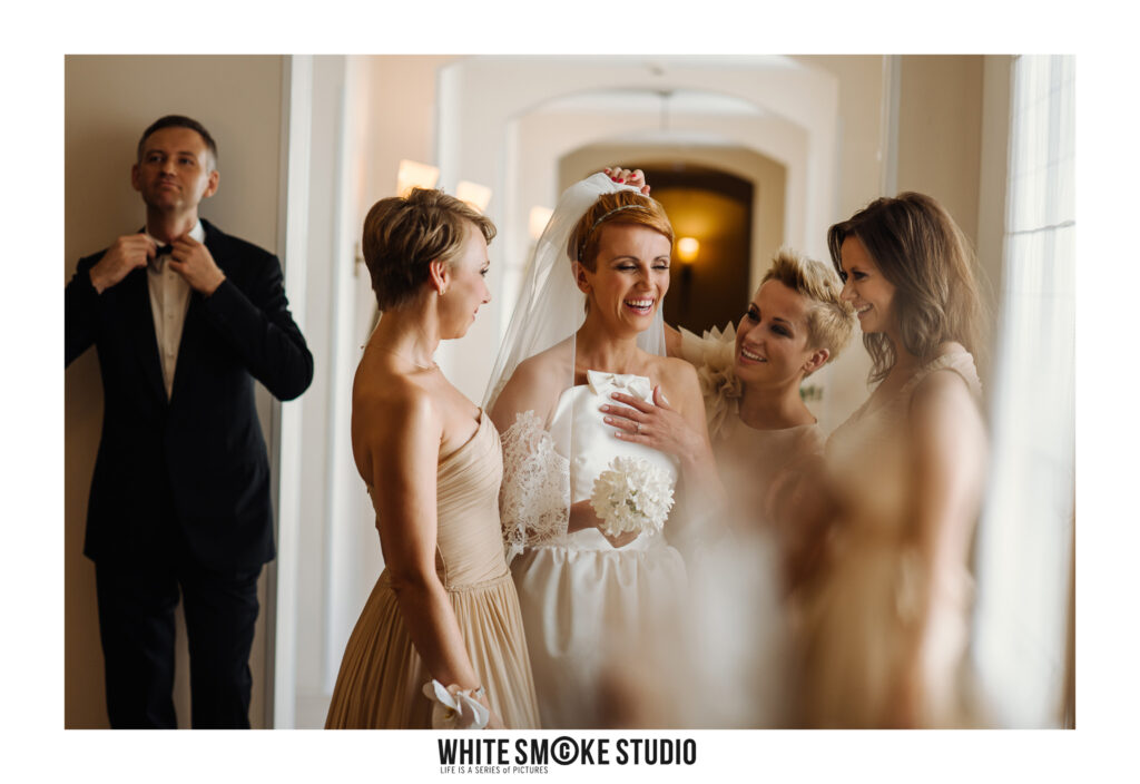 Reporterska fotografia ślubna - WhiteSmoke Studio 5 Śmiejąca się panna młoda z bliskimi podczas przygotowań